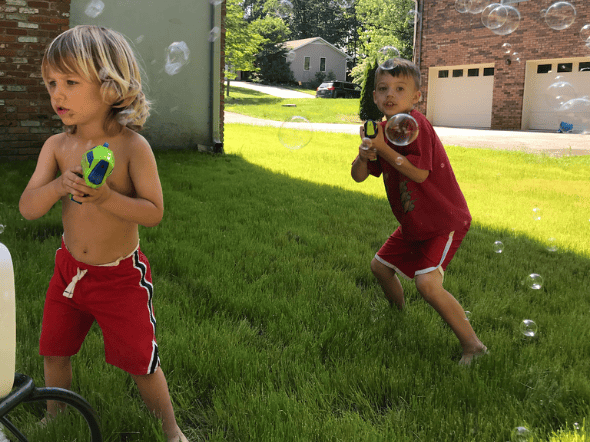 toddler and preschooler playing with bubbles outside