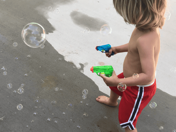 toddler playing with bubbles outside to stay busy
