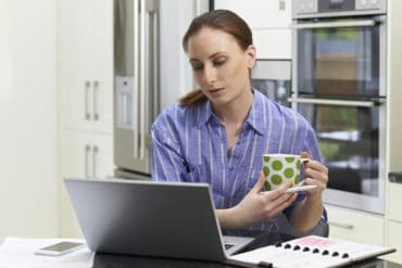 A woman works at a laptop in a home.
