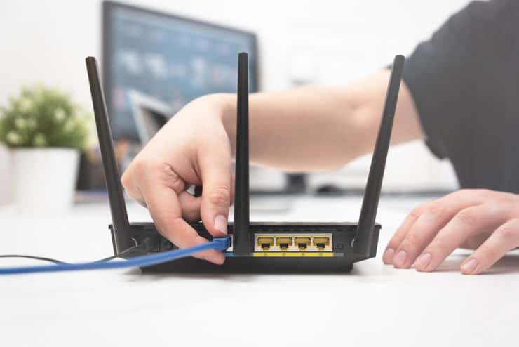 A person plugs an ethernet cable into a router.