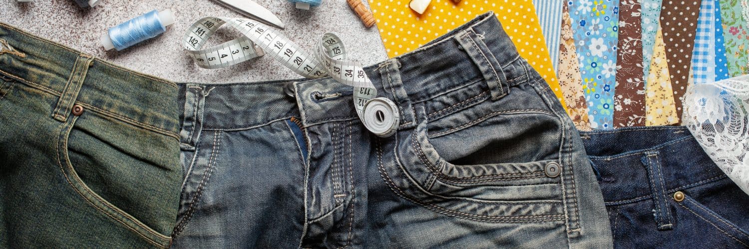 A pair of jeans is laid out with some upcycling supplies.