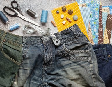A pair of jeans is laid out with some upcycling supplies.